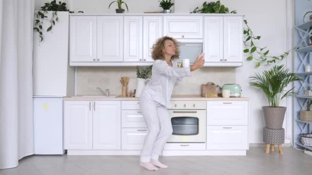 Посміхаючись гарненька жінка приймає Селфі на кухні з мобільним телефоном — стокове відео