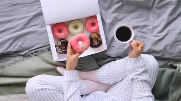 ท็อปวิวของผู้หญิงมีอาหารเช้าในเตียงกับกาแฟและโดนัท — วีดีโอสต็อก