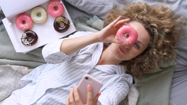 Jovem mulher tomando selfie no cama com donuts — Vídeo de Stock