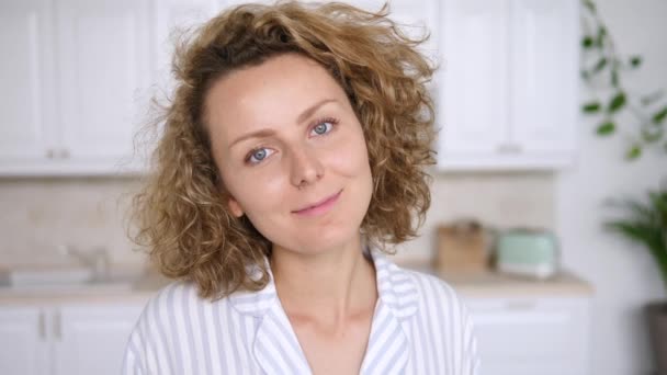 Portret van een jonge glimlachende vrouw die thuis naar de camera kijkt — Stockvideo