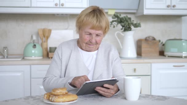 Sorrindo mulher sênior usando Tablet computador relaxante em casa — Vídeo de Stock