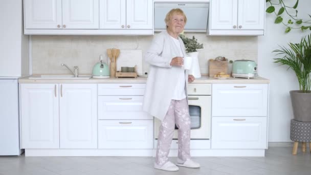 Fröhliche ältere Frau tanzt in der Küche. Lustige Großmutter. — Stockvideo