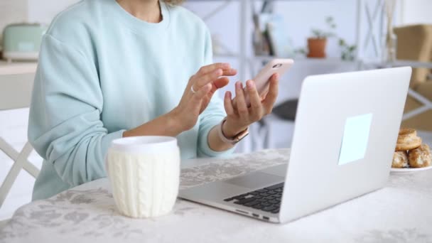Mujer usando Smartphone y Laptop. Espacio de trabajo en casa para el aprendizaje electrónico y el trabajo remoto . — Vídeos de Stock