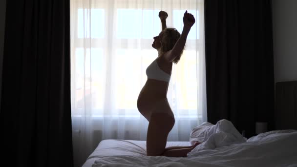 年轻孕妇舒展筋骨，躺在床上醒来 — 图库视频影像