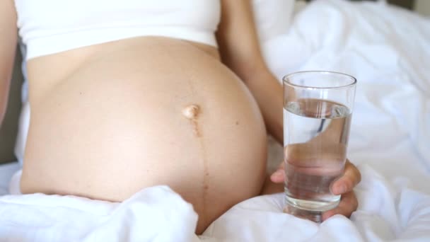 Primo piano di gravidanza donna pancia e vetro di acqua — Video Stock