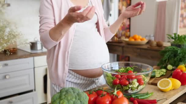 Концепция питания беременных. Беременная женщина готовит еду на кухне, делает салат . — стоковое видео