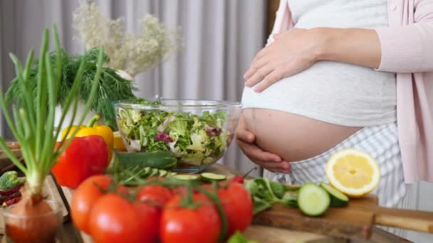 Schwangere bereitet in der Küche eine gesunde Mahlzeit zu. Großaufnahme des Bauches. — Stockvideo