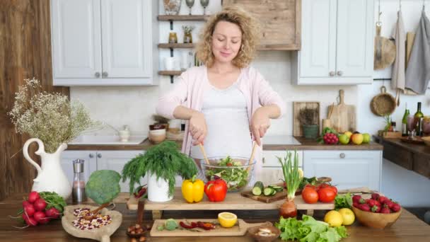 Щаслива вагітна жінка готує здоровий салат на кухні . — стокове відео