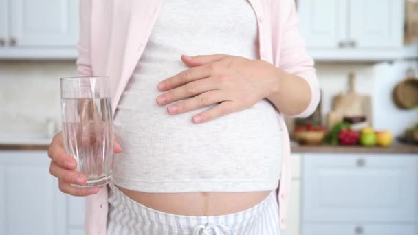 Mujer embarazada sosteniendo un vaso de agua en la cocina . — Vídeos de Stock