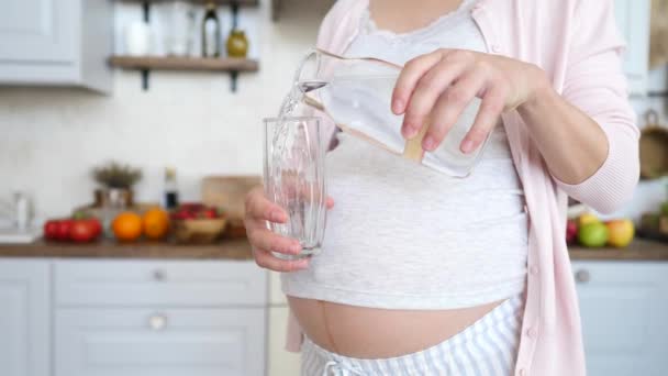 Closeup van zwangere vrouw gieten water in glas te blijven gehydrateerd. — Stockvideo