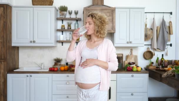 Schwangere trinkt morgens Wasser in Küche. — Stockvideo