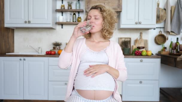 Femme enceinte boire de l'eau dans la cuisine. Déshydratation pendant la grossesse Concept . — Video