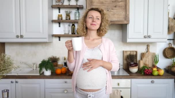 Donna incinta felice con tazza che beve tè in cucina. Buongiorno. Buongiorno. . — Video Stock