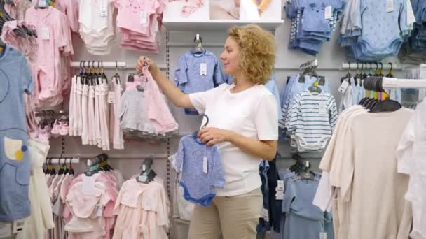 Ibu Buying Bayi yang hamil mengenakan pakaian bayi di toko pakaian Childrens. Minsk, Belarus, 22 Juni 2019 . — Stok Video