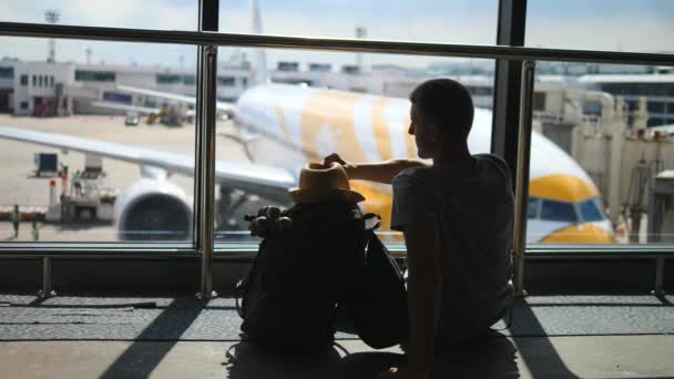 Jonge man Traveler In Hat Met Rugzak Kijkend naar Vliegtuig In Luchthaven — Stockvideo