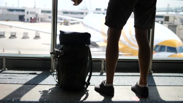 Toerist met rugzak op vakantie in de luchthaven staande tegen vliegtuigen — Stockvideo