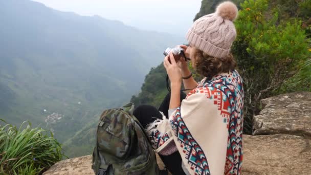Mujer joven viajero con mochila tomando fotos con cámara en la cima de la montaña — Vídeos de Stock