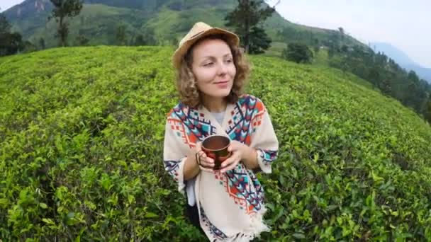 Glad kvinnlig resenär promenader på te plantering med kopp te — Stockvideo