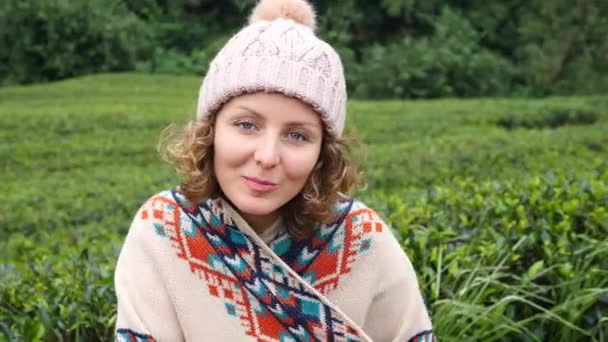 Молодая женщина улыбается портрет глядя на камеру в зеленом поле — стоковое видео
