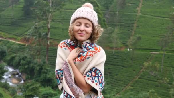 Donna viaggiatore in cappello sorridente a macchina fotografica in montagne verdi — Video Stock