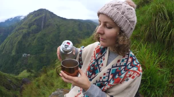 Cestovatel žena v Poncho pití čaje při kempování v horách — Stock video