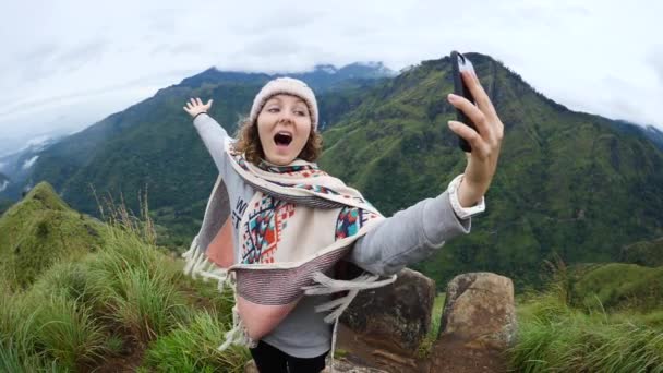Caminhante mulher no poncho tomando selfie com celular em montanhas — Vídeo de Stock