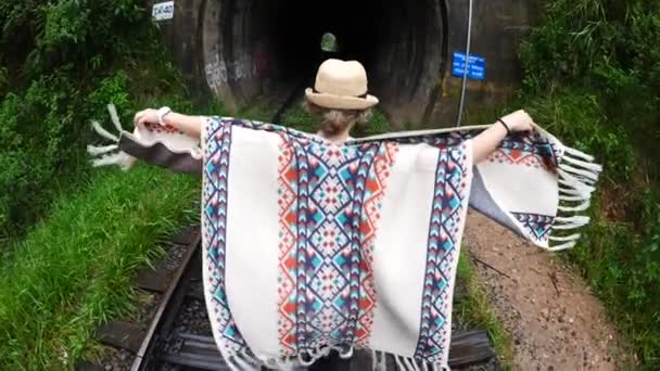 Reiziger in Poncho loopt in tunnel op spoorweg — Stockvideo