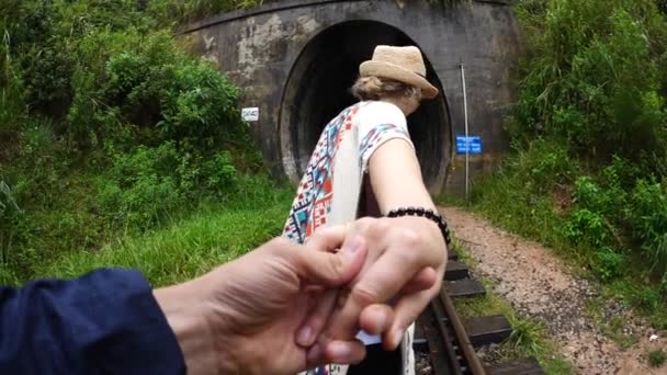 Ταξιδιώτρια γυναίκα κρατώντας τον άνθρωπο με το χέρι με τα πόδια στο σιδηρόδρομο. Ακολουθήστε με — Αρχείο Βίντεο
