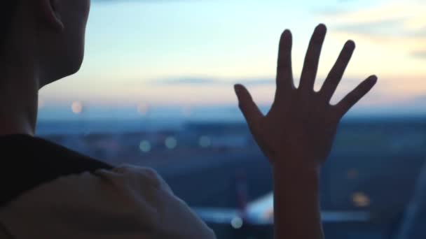 Női kéz az ablakban a repülőtéren a repülőgép ellen naplementekor — Stock videók