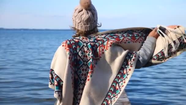 Mujer viajero usando poncho de punto corriendo en muelle en el agua — Vídeos de Stock