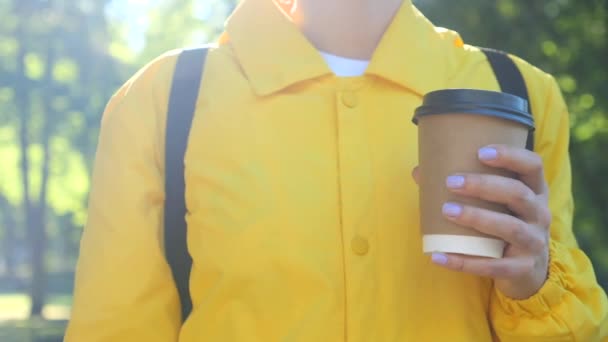 Nő pozitív sárga kabát tartó papír csésze kávé szabadban — Stock videók