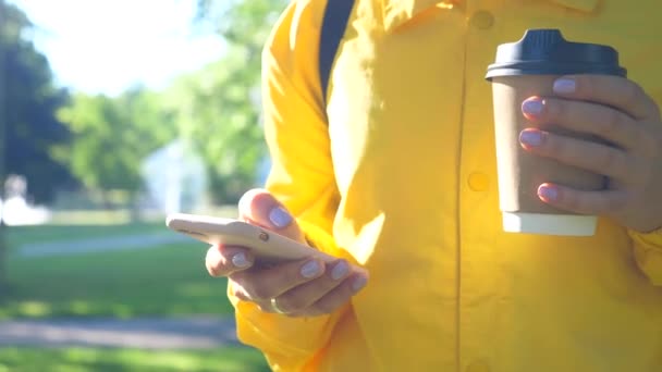 Closeup ležérní žena pomocí mobilního telefonu s šálkem kávy v ruce — Stock video