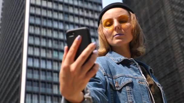 Glad ung kvinna som tar selfie med hjälp av telefon i modern stad — Stockvideo