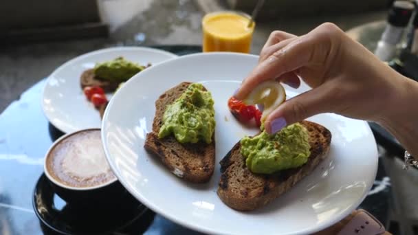 Kvinna Hand Squeezing Lemon på hälsosam frukost rostat bröd med Avokado Smash — Stockvideo
