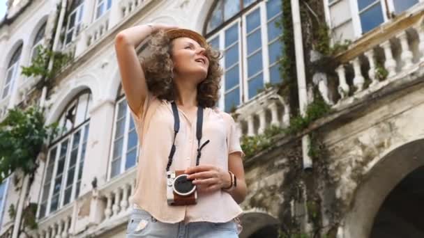 Hipster toeristische meisje in hoed sightseeing met camera in de stad op zomervakantie — Stockvideo