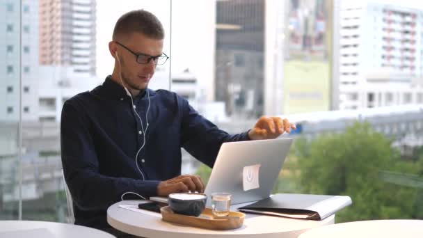 커피 휴게실에서 노트북 컴퓨터로 일하는 잘생긴 백인 남자 — 비디오