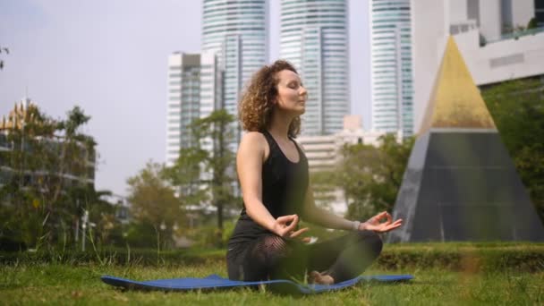 Kobieta medytująca w parku w mieście — Wideo stockowe