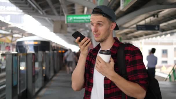 Hombre joven hablando por mensajes de voz en el teléfono celular conmutando en la ciudad — Vídeo de stock