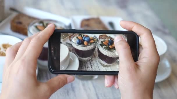 スマートフォンで食べ物の写真を撮る女性の手.朝食のためのビーガンチーズプリン. — ストック動画