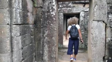 Genç bayan turist Antik Angkor Wat Tapınağını geziyor.