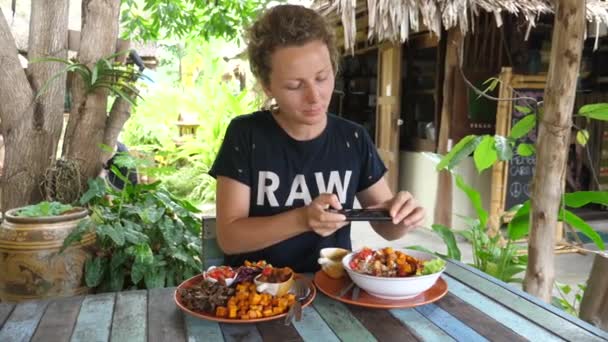 Unga kvinnliga Travel Food Blogger Fotografera sin lunch med smartphone i restaurang — Stockvideo