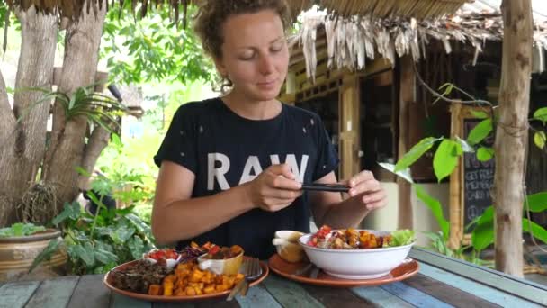 Jonge vrouw neemt foto van voedsel met telefoon in gezond veganistisch restaurant buiten — Stockvideo