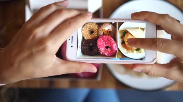 Kadın Eller cep telefonuyla yemek fotoğrafı çekiyor. Donutların Yemek Fotoğrafı. — Stok video