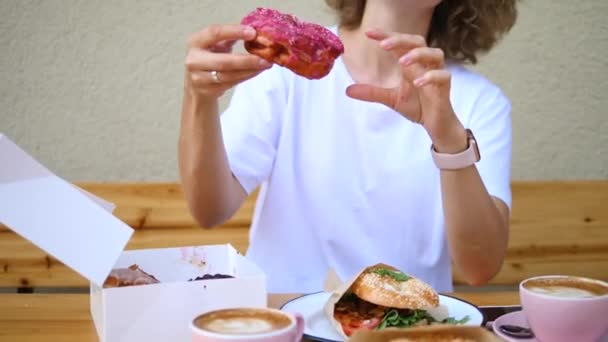 Ελκυστική ξανθιά γυναίκα τρώει ροζ ντόνατ. — Αρχείο Βίντεο