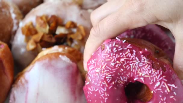 Жіноча рука бере рожевий пончик з блискітками. Крупним планом . — стокове відео