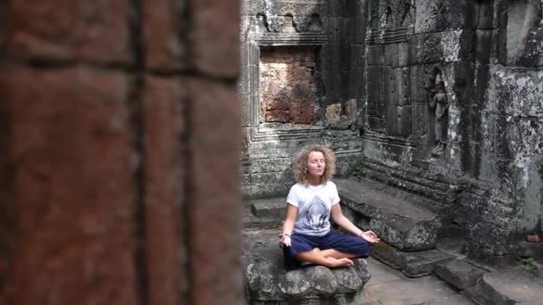 Mladá žena meditující v lotosu v antickém chrámu Angkor Wat — Stock video