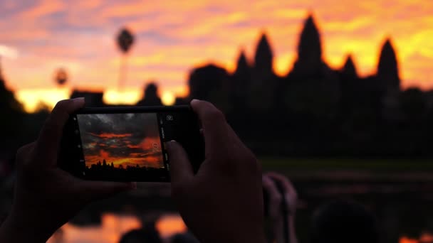 Podróżnik robi zdjęcie starożytnej świątyni Angkor Wat o wschodzie słońca — Wideo stockowe