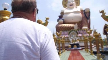 Hotei ya da Budai Tanrı 'ya dua eden kıdemli turist. Şişko Buda manzarası.