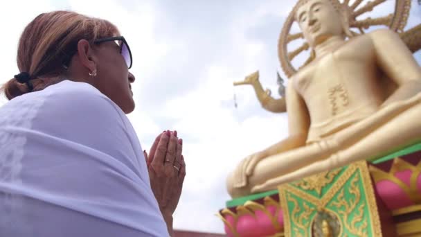 Seniorin betet vor Buddha-Statue — Stockvideo