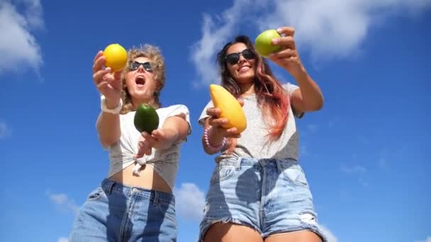 Zwei schöne junge Frauen tanzen am Strand mit gesunden Früchten — Stockvideo